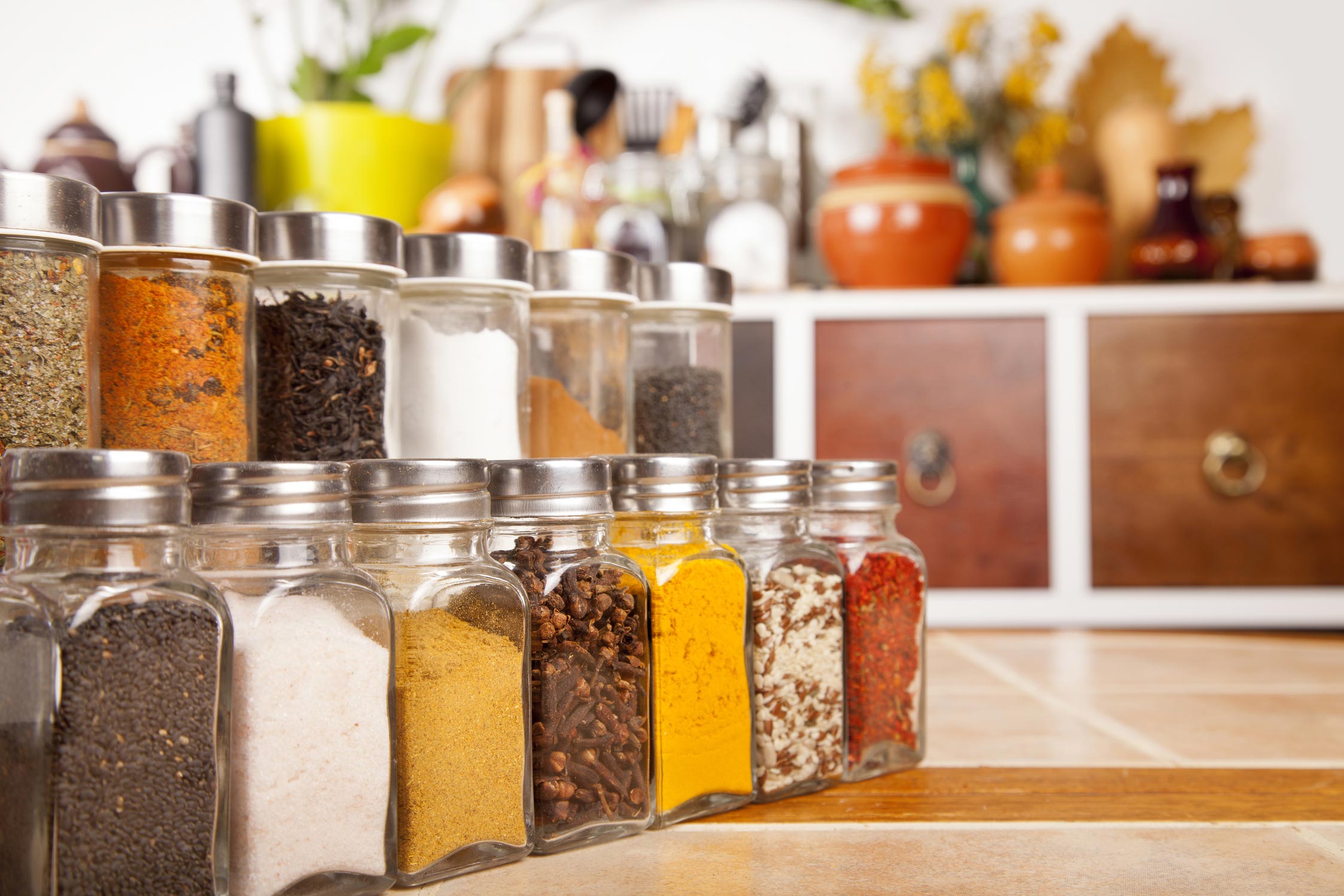 Glass jars filled with colorful spices including turmeric, cloves, and chili on a kitchen counterGlass jars filled with colorful spices including turmeric, cloves, and chili on a kitchen counter