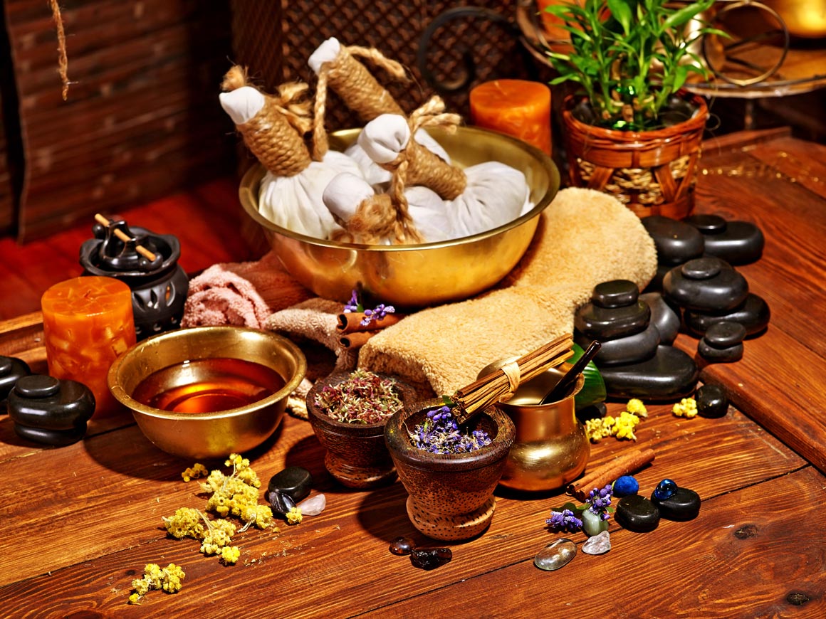 Ayurvedic herbal compress pouches, warming oils, and dried botanicals for Kapha balancing